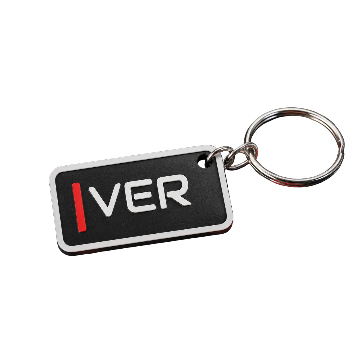 A close-up of a rectangular keychain with a black face, white border, and the word "IVER" in white with a red vertical accent. The keychain is attached to a silver metal key ring and rests on a black, red, and white patterned surface with a checkered fabric in the background.